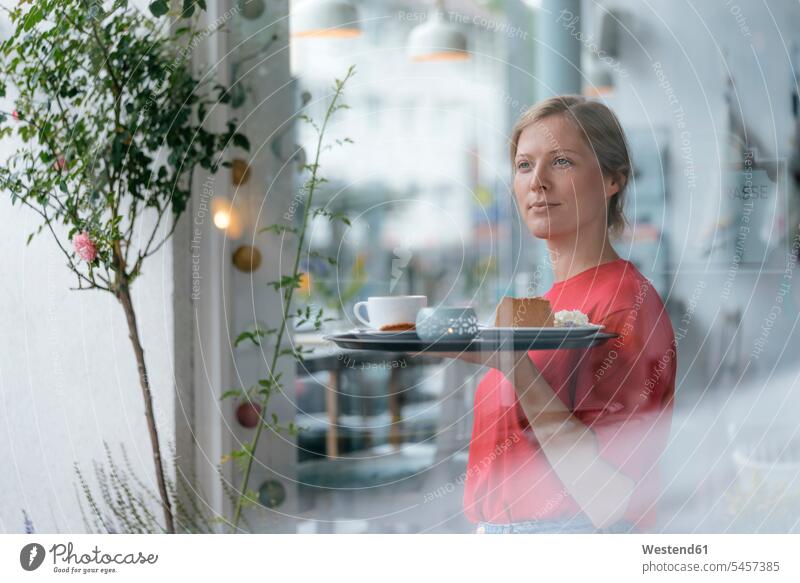 Junge Frau serviert Kaffee und Kuchen in einem Cafe servieren Kaffeehaus Bistro Cafes Café Cafés Kaffeehäuser weiblich Frauen Getränk Getraenk Getränke
