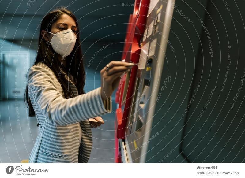 Weibliche Passagierin mit Gesichtsmaske beim Ticketkauf am Kiosk während COVID-19 Schutzmaske Schutzmasken Maske Masken Infektion Infektionskrankheit