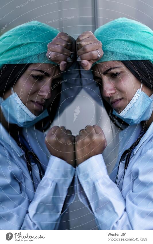 Trauriger Arzt mit Gesichtsmaske an Glaswand des Krankenhauses gelehnt Farbaufnahme Farbe Farbfoto Farbphoto Außenaufnahme außen draußen im Freien Tag