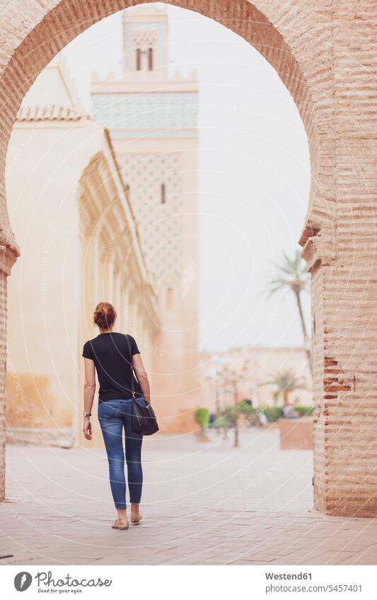 Marokko, Marrakesch, Rückenansicht einer Frau mit Blick auf die Kasbah-Moschee reisen verreisen Moscheen Minarett Minarette Umhängetasche Reisende Reisender