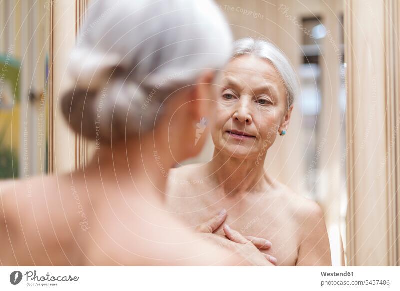 Ältere Frau schaut ihr Spiegelbild an Spiegelbilder Seniorin älter Seniorinnen alt weiblich Frauen ansehen Senioren Erwachsener erwachsen Mensch Menschen Leute