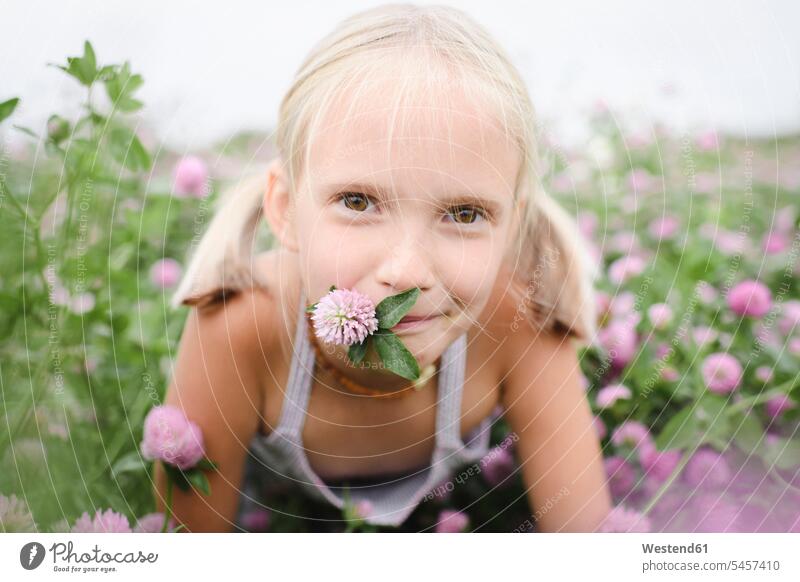 Bildnis eines lächelnden Mädchens mit Kleeblume im Mund sommerlich Sommerzeit freuen Glück glücklich sein glücklichsein zufrieden lilafarben violett Muße