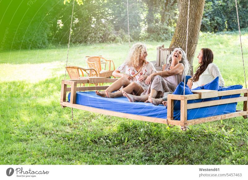 Frauen einer Familie entspannen im Garten, sitzen auf einer Schaukel Bett Deutschland nur Frauen Bettschaukel schöne Frau schöne Frauen Lebensqualität