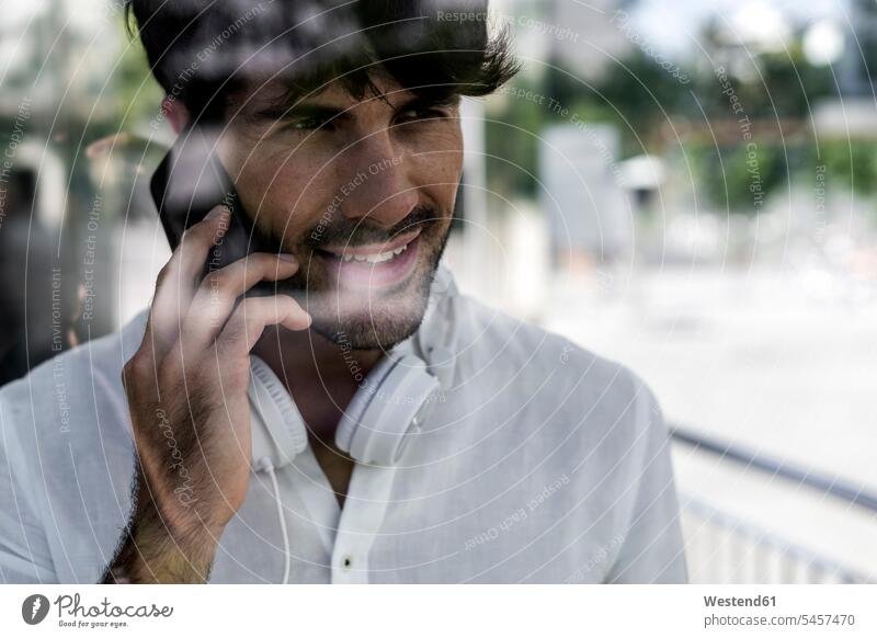 Porträt eines jungen Mannes am Handy in der Stadt Portrait Porträts Portraits telefonieren anrufen Anruf telephonieren Männer männlich staedtisch städtisch