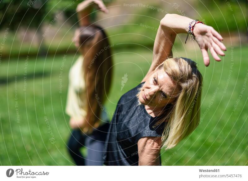 Reife Frau macht Yoga mit ihrer Tochter in einem Park Leute Menschen People Person Personen Europäisch Kaukasier kaukasisch 2 2 Menschen 2 Personen zwei