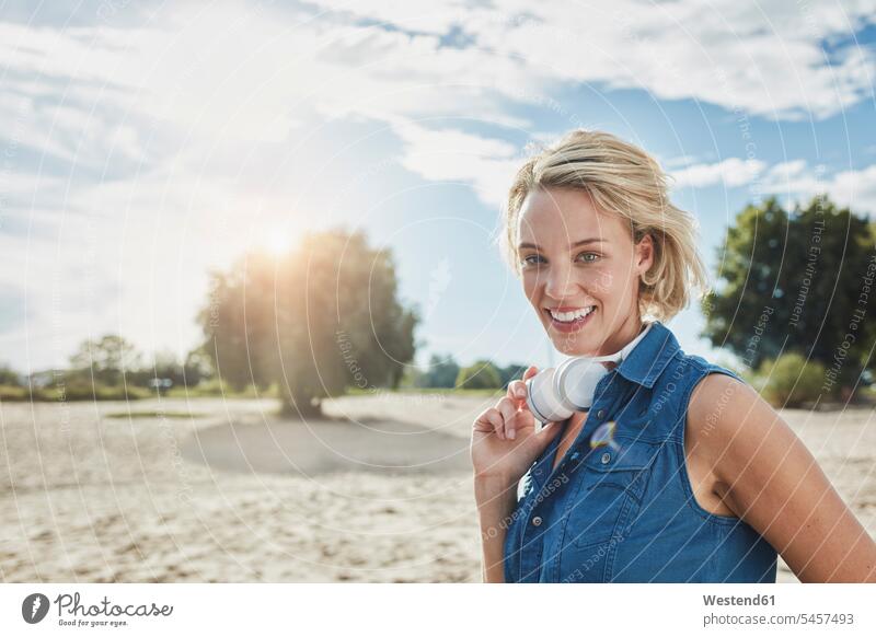 Porträt einer glücklichen jungen Frau mit Kopfhörern am Strand Kopfhoerer Beach Straende Strände Beaches weiblich Frauen Portrait Porträts Portraits Glück