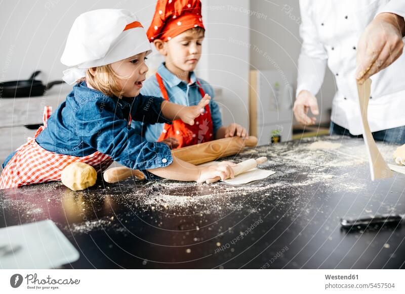 Vater mit zwei Kindern bereitet zu Hause in der Küche Teig für selbstgemachte glutenfreie Nudeln zu Gastronomie Koeche Kuechenchef Kuechenchefs Köche Küchenchef
