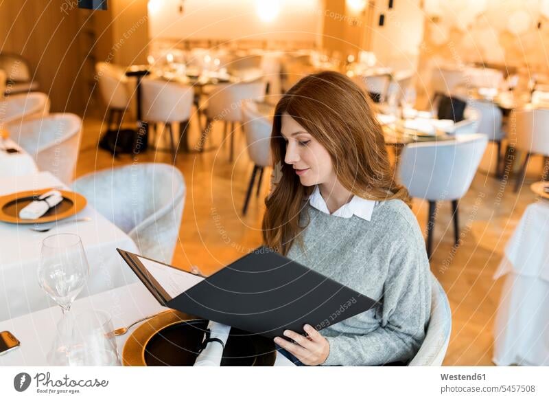 Frau sitzt am Tisch in einem Restaurant und liest die Speisekarte Lokal Speiserestaurant Lokale Speiselokale Restaurants Speiserestaurants weiblich Frauen