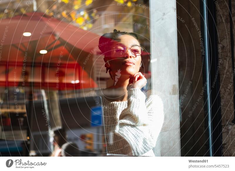 Selbstbewusste junge Frau mit Brille schaut durch das Fenster eines Cafés Farbaufnahme Farbe Farbfoto Farbphoto Spanien Außenaufnahme außen draußen im Freien