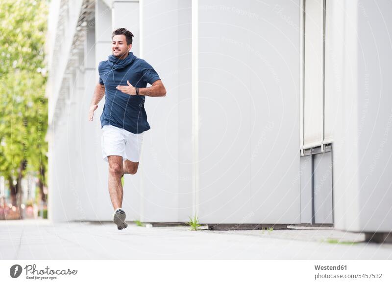 Junger Mann joggt in der Stadt blaue blauer blaues Muße Anreiz Ansporn Antrieb motivieren motiviert außen draußen im Freien staedtisch städtisch Urbanität