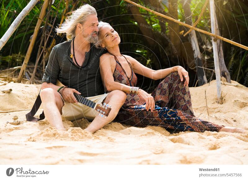 Porträt der glücklichen Senior Hippie-Paar mit Gitarre entspannen am Strand Entspannung relaxen Beach Straende Strände Beaches Seniorenpaar älteres Paar
