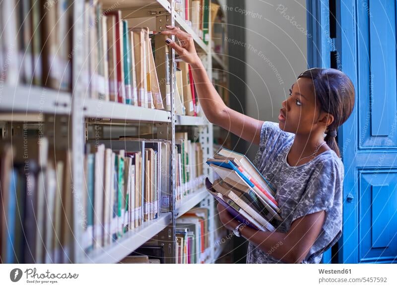 Junge Frau prüft die Bücher in den Regalen der Nationalbibliothek, Maputo, Mosambik Buch Bücherregal lernen lesen studieren stehen Stapel Wissen Auswahl