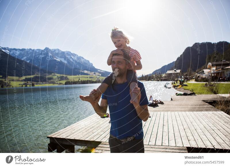 Österreich, Tirol, Walchsee, glücklicher Vater trägt Tochter auf den Schultern am See Familie Familien tragen transportieren Seen Glück glücklich sein