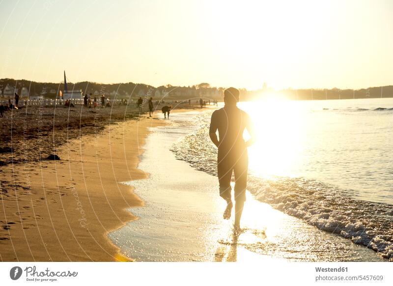 Mann joggt am Strand bei Sonnenuntergang laufen rennen Jogger Rückansicht Rueckansicht Rückenansicht Rueckenansicht von hinten Sonnenuntergänge Beach Straende