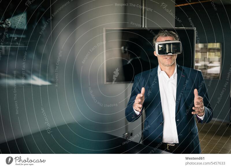 Reifer Geschäftsmann mit VR-Brille im Büro Office Büros Businessmann Businessmänner Geschäftsmänner Brillen Virtuelle Realität Virtuelle Realitaet Arbeitsplatz