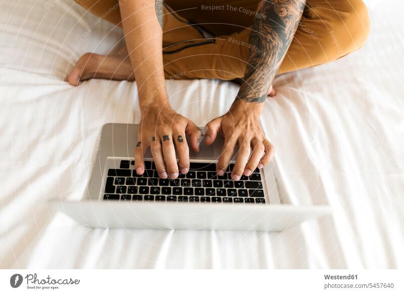 Nahaufnahme eines tätowierten Mannes mit Laptop im Bett Betten Notebook Laptops Notebooks sitzen sitzend sitzt Männer männlich Tattoo Tätowierungen Tatoos