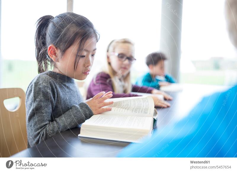 Schulmädchen liest Buch auf dem Tisch im Pausenraum der Schule lesen Schülerin Schulkind Bildung Hobby smart positiv vier Personen Asiatin Wissen Freizeit