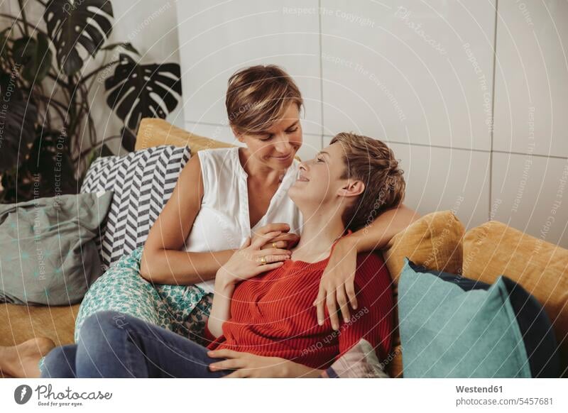 Glückliches lesbisches Paar kuschelnd auf Couch glücklich glücklich sein glücklichsein Pärchen Paare Partnerschaft schmusen knuddeln Sofa Couches Liege Sofas