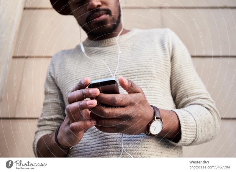 Mittlerer erwachsener Mann, der ein Smartphone benutzt und Musik hört Uhren Armbanduhren Telekommunikation telefonieren Handies Handys Mobiltelefon