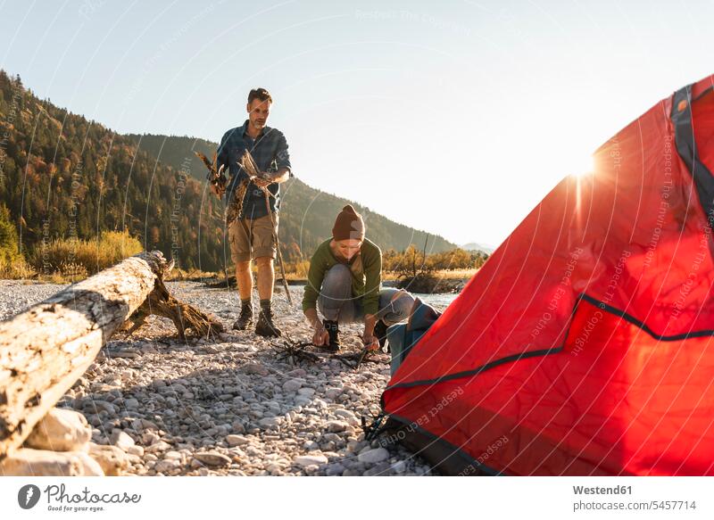 Reifes Paar Camping am Flussufer, Holz sammeln für ein Lagerfeuer Campen zelten Abenteuer abenteuerlich Naturerlebnis Zelt Zelte hoelzern hölzern Pärchen Paare