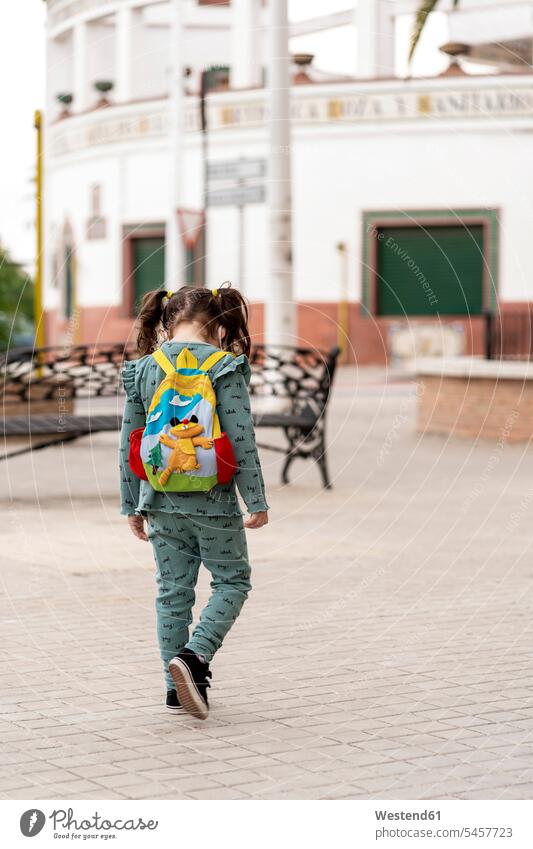 Rückansicht eines Mädchens, das mit Rucksack und Maske auf dem Platz geht Leute Menschen People Person Personen Kinder Rucksäcke gehend Muße geschützt schützen