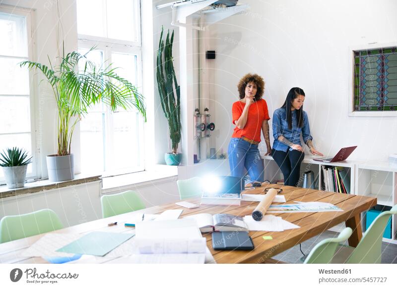 Zwei Frauen in modernem Büro mit Videoprojektor auf dem Tisch Job Berufe Berufstätigkeit Beschäftigung Jobs geschäftlich Geschäftsleben Geschäftswelt