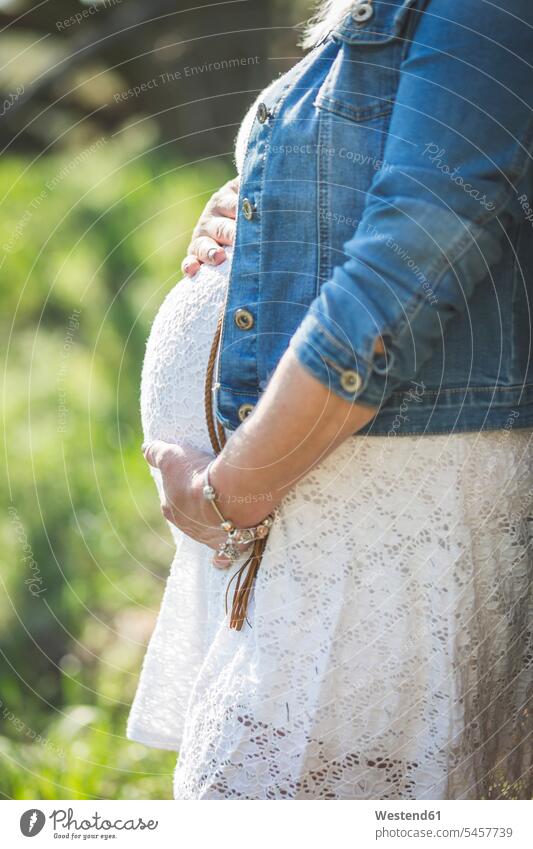 Schwangere Frau hält ihren Bauch, Nahaufnahme Kleid Kleider Jeansjacke Jeansjacken nicht erkennbare Person nicht erkennbare Personen unkenntliche Person