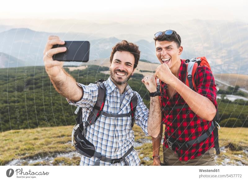 Italien, Monte Nerone, zwei glückliche Wanderer auf dem Gipfel eines Berges, die ein Selfie machen Mann Männer männlich Selfies wandern Wanderung Berggipfel