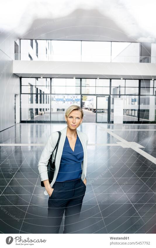 Erfolgreiche Geschäftsfrau steht in der Eingangshalle eines Bürogebäudes und schaut in die Kamera Job Berufe Berufstätigkeit Beschäftigung Jobs geschäftlich