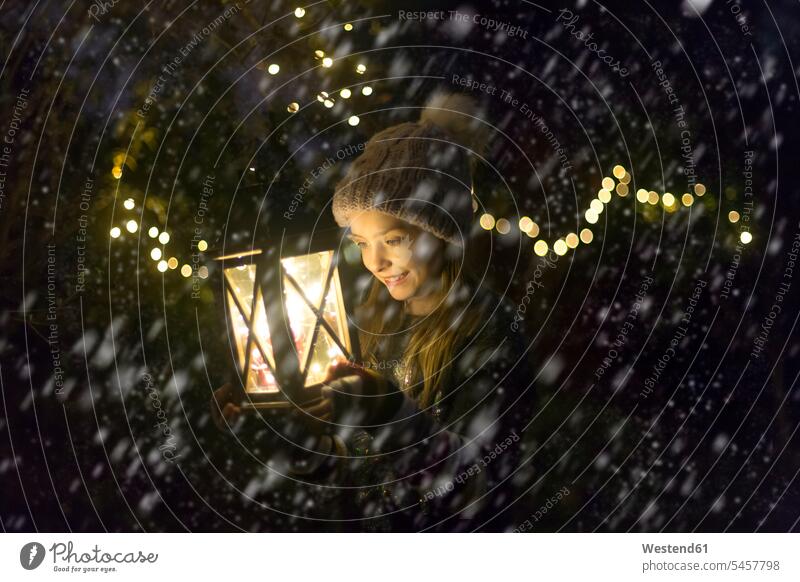 Glückliches Mädchen mit brennender Laterne in der Nacht bei Schneefall weiblich Portrait Porträts Portraits Laternen beleuchtet Beleuchtung nachts Kind Kinder