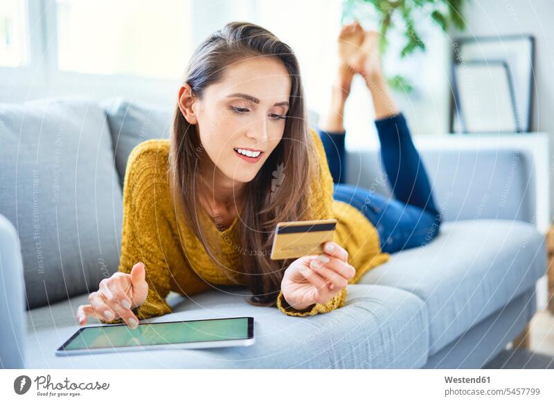 Schöne lächelnde Frau kauft online mit Tablette und Kreditkarte Leute Menschen People Person Personen Alleinstehende Alleinstehender Singles Unverheiratete