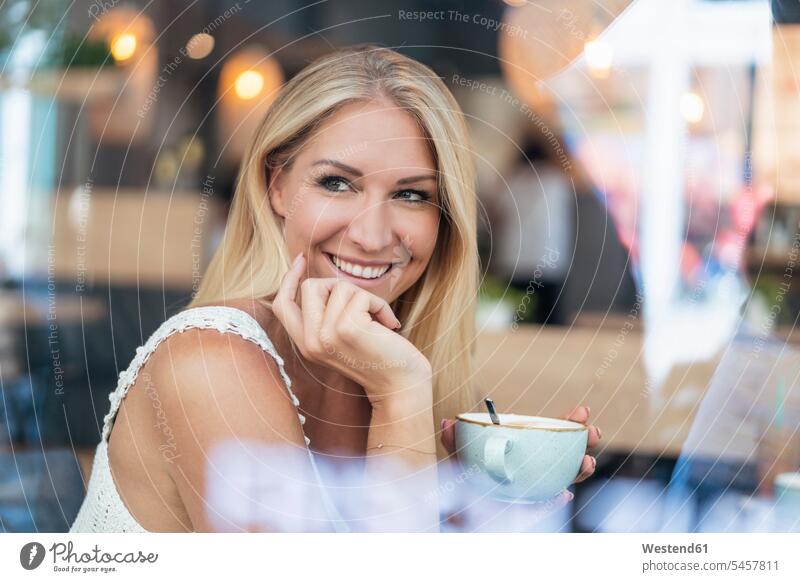 Porträt einer lächelnden blonden Frau beim Kaffeetrinken in einem Café Leute Menschen People Person Personen Alleinstehende Alleinstehender Singles