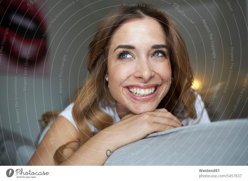 Porträt einer glücklichen jungen Frau auf der Couch Sofa Couches Liege Sofas lächeln weiblich Frauen Glück glücklich sein glücklichsein lachen Erwachsener