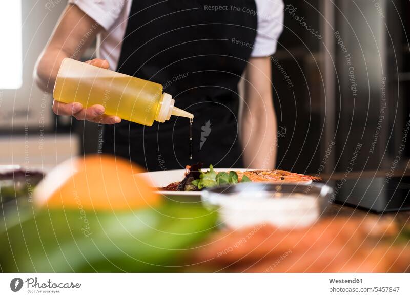 Nahaufnahme von Frau Kochen in der Küche gießen Olivenöl auf ein Gericht Spanien zubereiten kochen Essen zubereiten differenzierter Fokus Wohnung wohnen