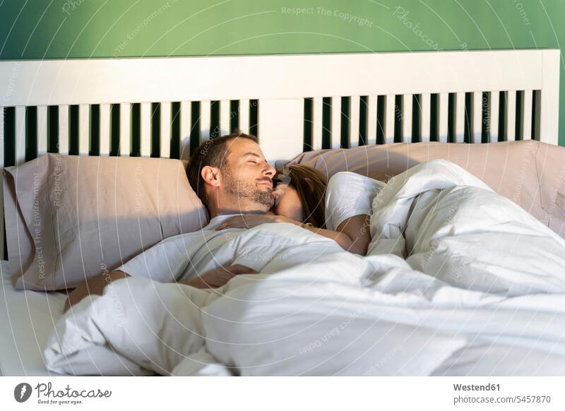 Frau umarmt Mann beim Schlafen auf dem Bett zu Hause Farbaufnahme Farbe Farbfoto Farbphoto Innenaufnahme Innenaufnahmen innen drinnen morgens Morgen früh Frühe