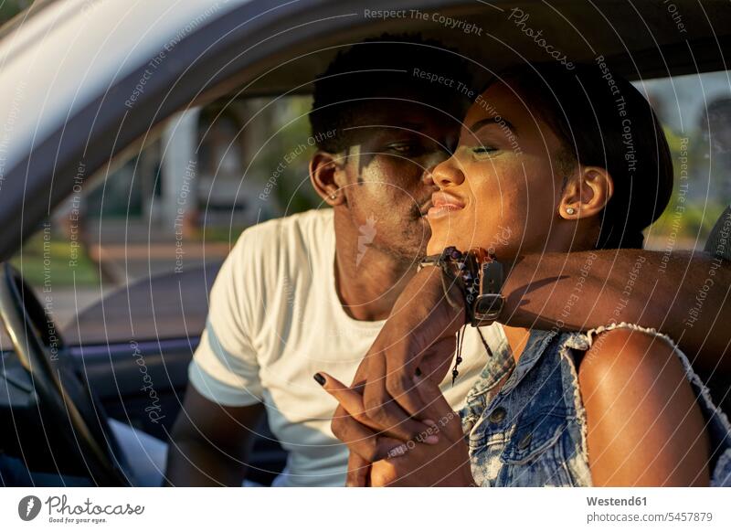 Junges Paar sitzt im Auto und küsst sich Transport Transportwesen KFZ Verkehrsmittel Automobil Autos PKW PKWs Wagen Kuss Küsse sitzend Glück glücklich sein