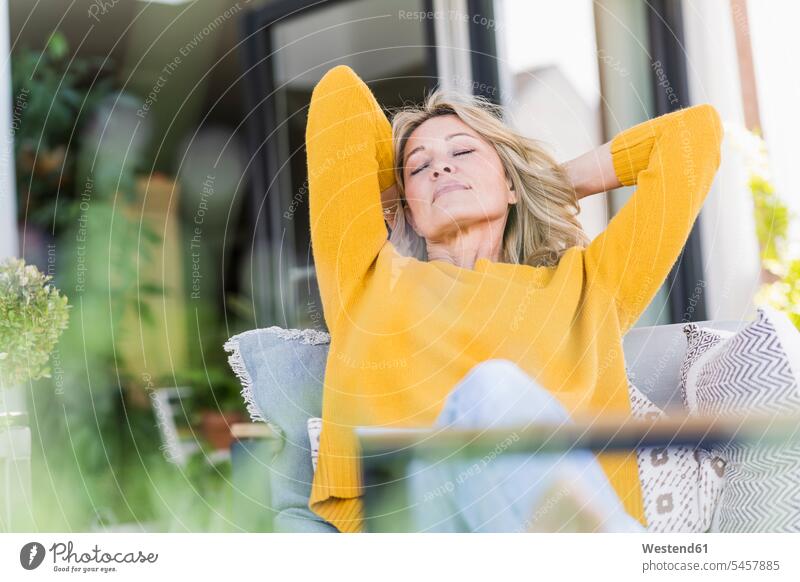 Porträt einer reifen Frau mit geschlossenen Augen beim Entspannen auf der Terrasse Stuehle Stühle entspannen relaxen sitzend sitzt geniessen Genuss Farben