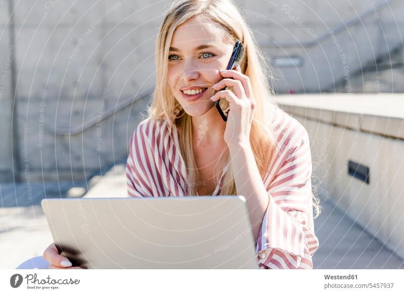 Porträt der lächelnden blonde junge Frau mit Laptop am Telefon im Freien weiblich Frauen Notebook Laptops Notebooks telefonieren anrufen Anruf telephonieren