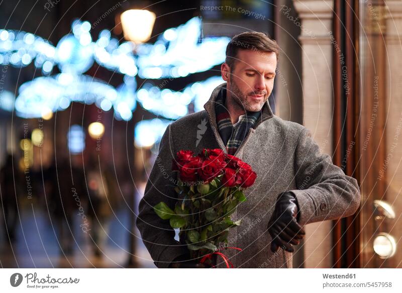 Porträt eines wartenden Mannes mit einem Strauß roter Rosen, der die Zeit kontrolliert Blumenstrauß Bouquet Blumenstrauss Blumensträusse Blumensträuße checken
