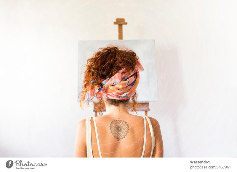 Rückansicht einer jungen Malerin in einem Kunstatelier vor einer leeren Leinwand Spanien Künstlerin Kuenstlerinnen Künstlerinnen Locken lockiges Haar