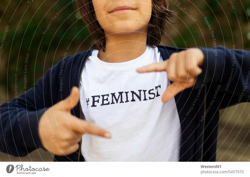 Kleiner Junge steht auf der Straße mit Aufdruck auf T-Shirt, sagt Feminist, macht Fingerabdruck T-Shirts stolz stolz sein Eingebung Ideen Text Coolness Waende