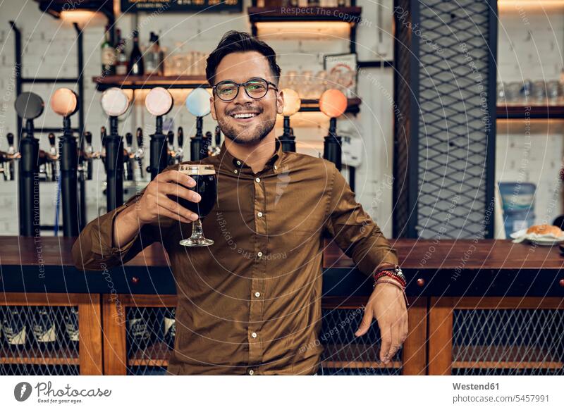 Porträt eines lächelnden Mannes, der in einer Kneipe sein Bierglas hebt Leute Menschen People Person Personen Europäisch Kaukasier kaukasisch 1 Ein ein Mensch