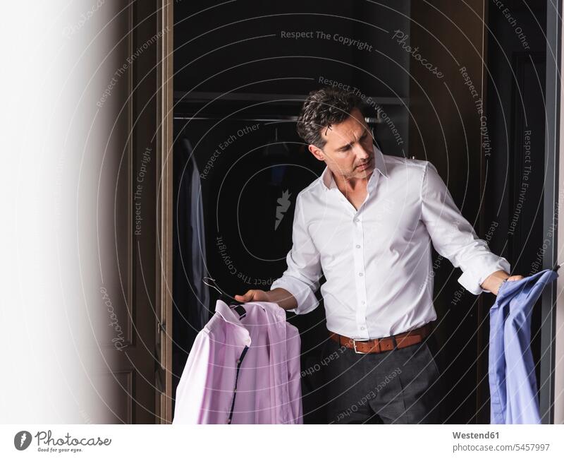 Geschäftsmann zieht sich zu Hause an und wählt Hemd aus der Garderobe Kleiderschrank Kleiderschränke Businessmann Businessmänner Geschäftsmänner Hemden Zuhause