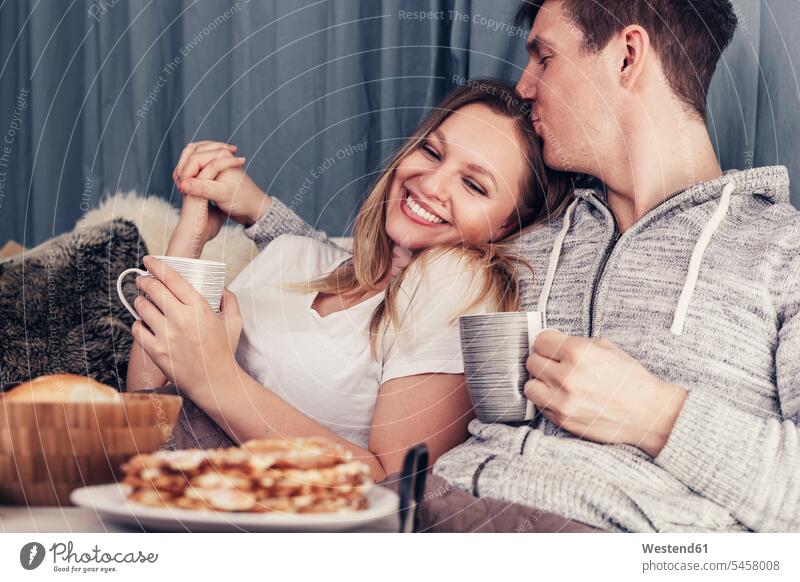 Zärtliches junges Paar beim Frühstück im Bett Betten Pärchen Paare Partnerschaft frühstücken entspannt entspanntheit relaxt Mensch Menschen Leute People