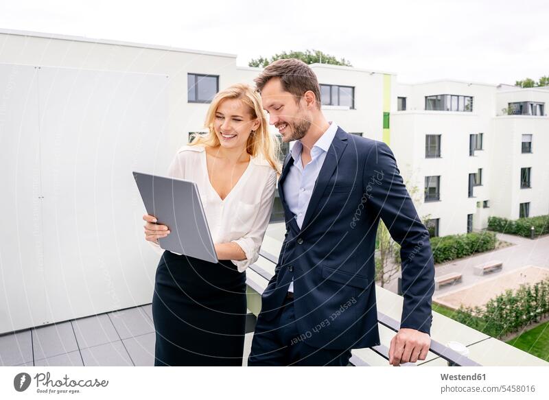 Immobilienmakler, der mit einem Kunden auf einem Balkon steht und auf ein digitales Tablet schaut stehen stehend Geschäftsfrau Geschäftsfrauen Businesswomen