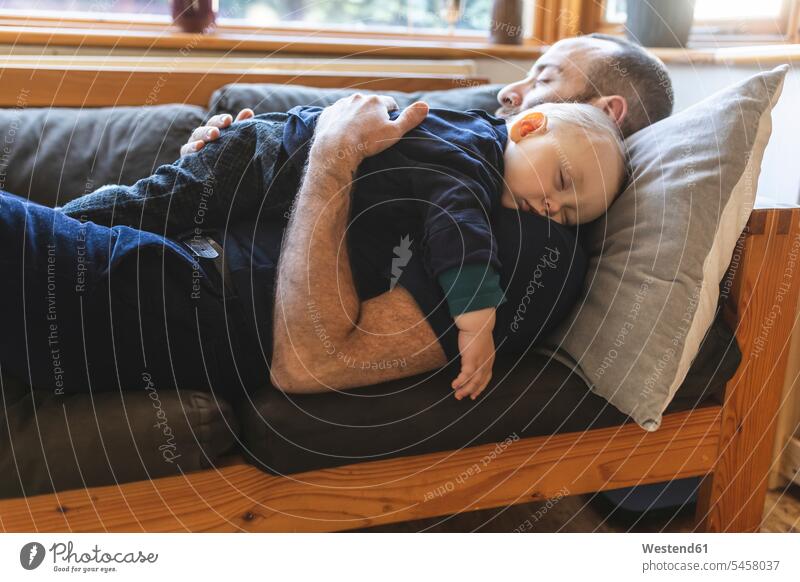 Vater und Sohn schlafen zusammen auf dem Sofa Polster Couch Couches Liege Sofas entspannen relaxen knuddeln schmusen schlafend Arm umlegen Umarmung Umarmungen
