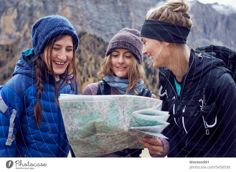 Drei glückliche junge Frauen wandern in den Bergen und schauen auf die Karte Karten Wanderung Freundinnen ansehen Glück glücklich sein glücklichsein weiblich