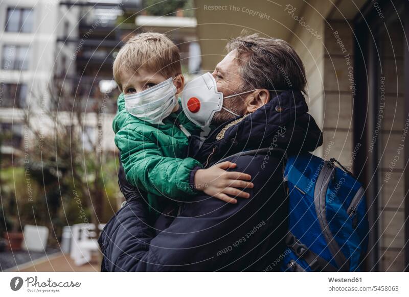 Vater trägt Sohn, beide tragen Schutzmasken, im Freien Rucksäcke Gesundheit Gesundheitswesen medizinisch Erkrankung Erkrankungen Krankheiten geschützt schützen