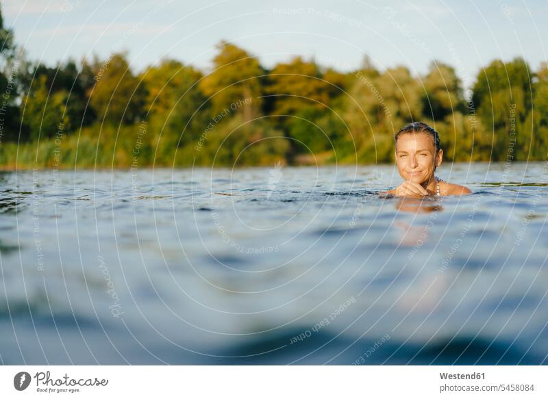 Porträt einer lächelnden Frau, die in einem See schwimmt weiblich Frauen Seen Portrait Porträts Portraits schwimmen Erwachsener erwachsen Mensch Menschen Leute