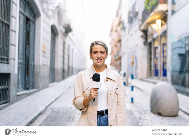 Journalistin spricht über Mikrofon, während sie in der Stadt auf der Straße steht Farbaufnahme Farbe Farbfoto Farbphoto Spanien Außenaufnahme außen draußen